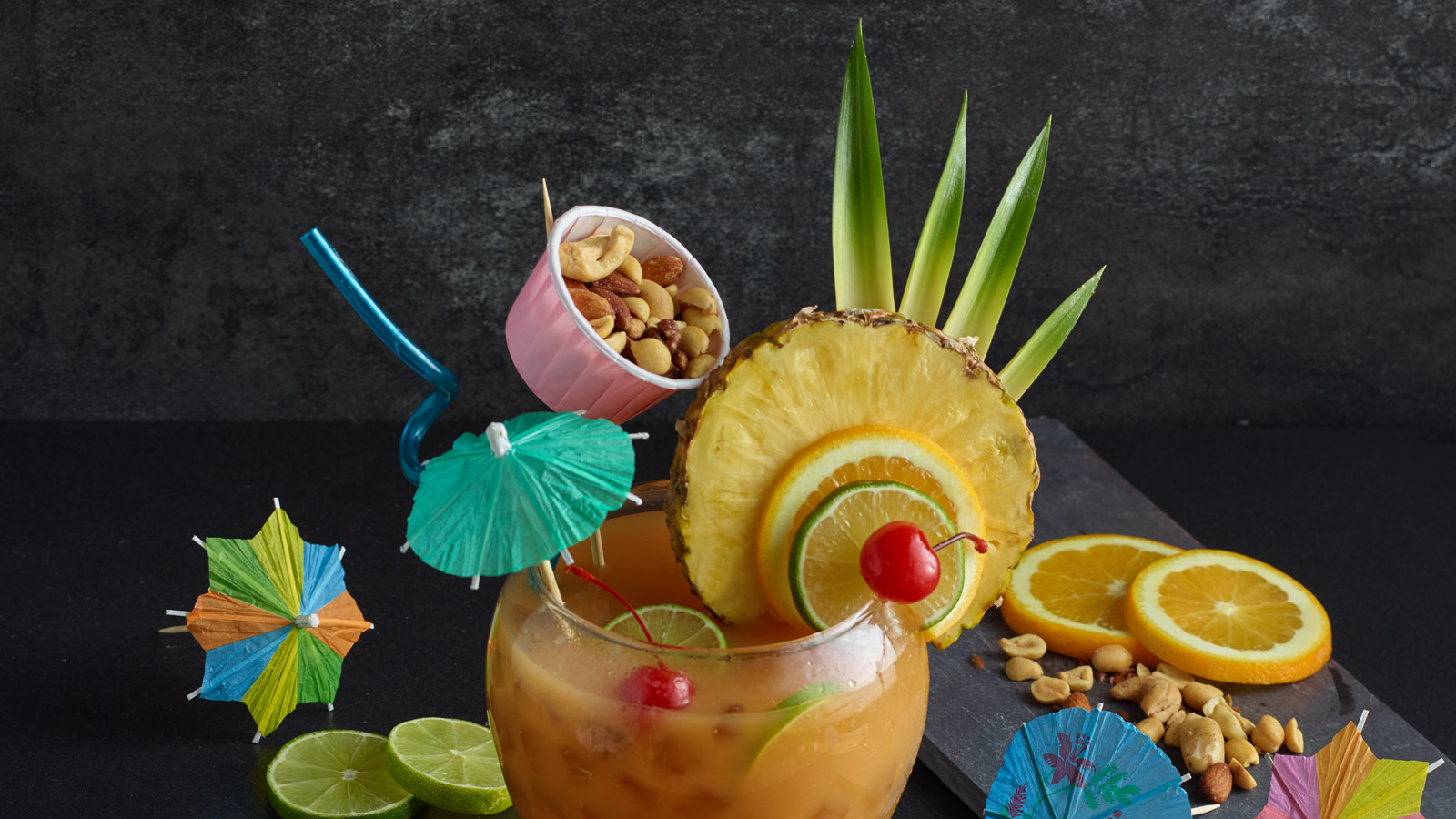 Glass of PLANTERS punch with fruit garnish and a small cup of nuts.