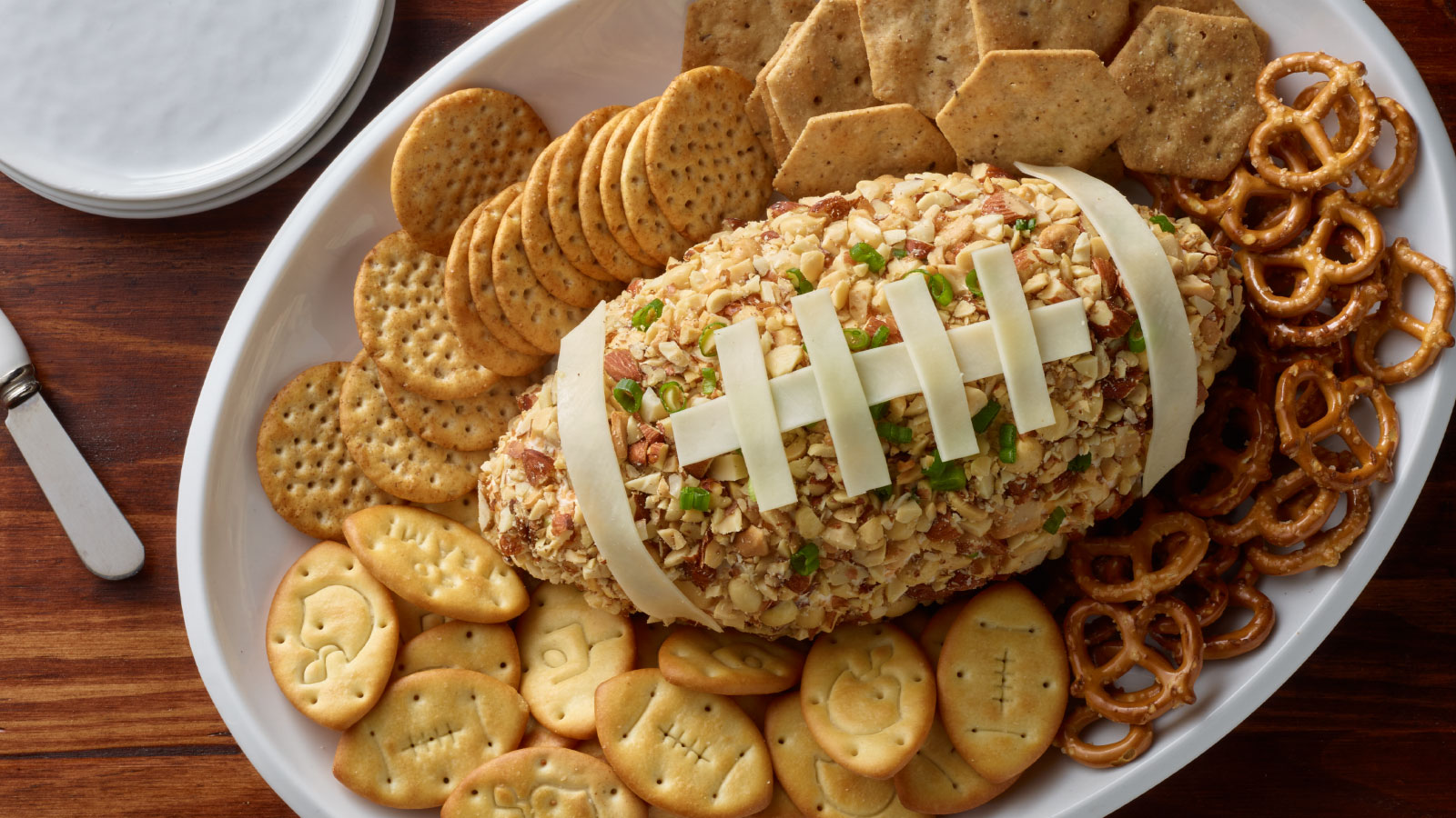 Football shaped cheese ball with crackers and pretzels.