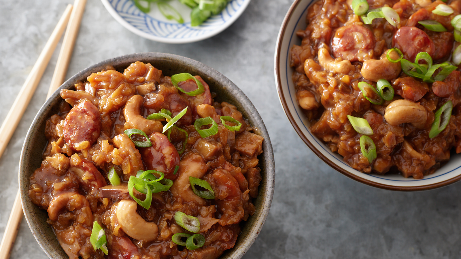 Bowls of Nuo Mi Fan topped with sliced green onions.