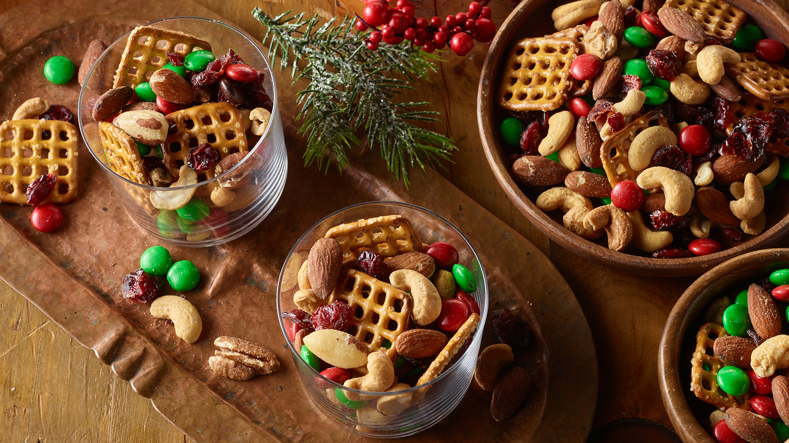 Clear glass cups and wooden bowls filled with PLANTERS holiday trail mix.