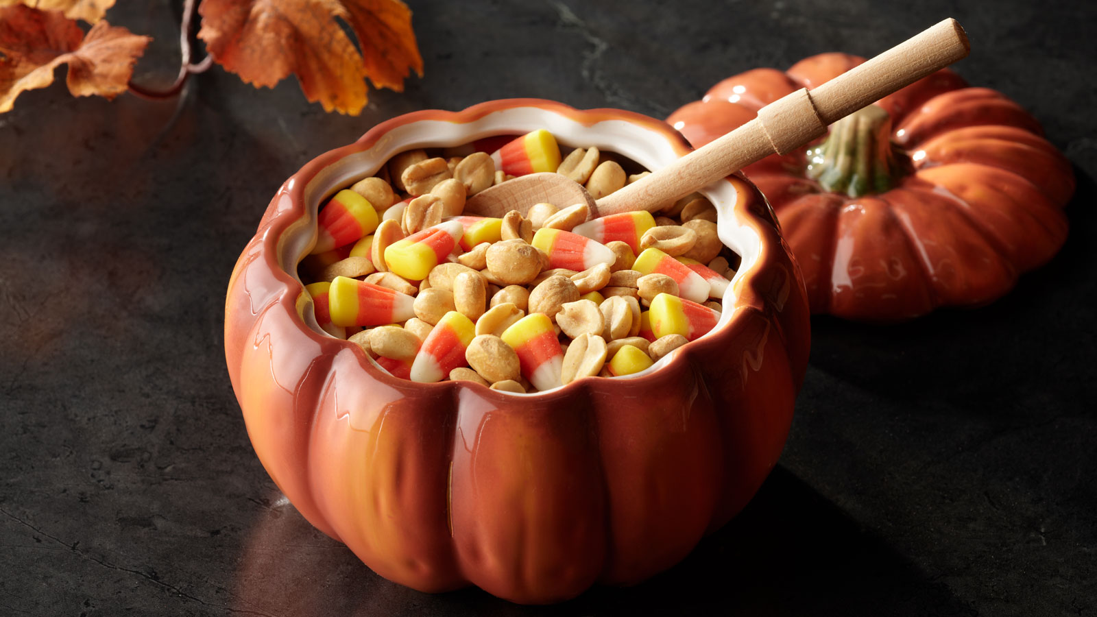 Ceramic pumpkin dish filled with Halloween peanuts and candy corn.