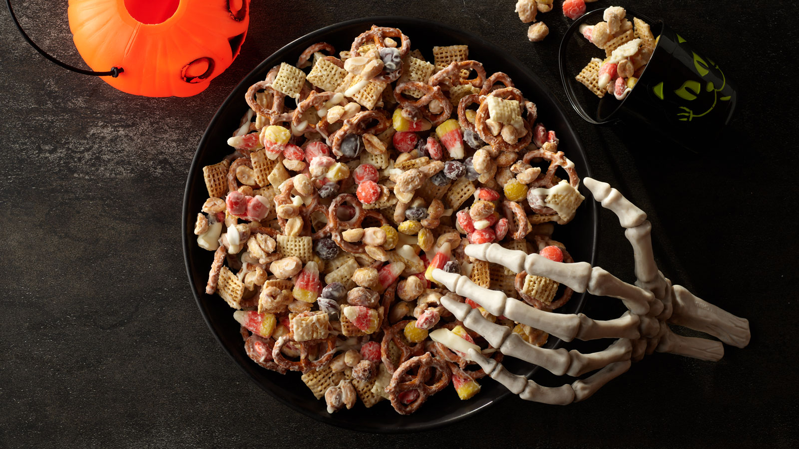 Large bowl of Halloween snack mix with a skeleton hand draped over the edge.