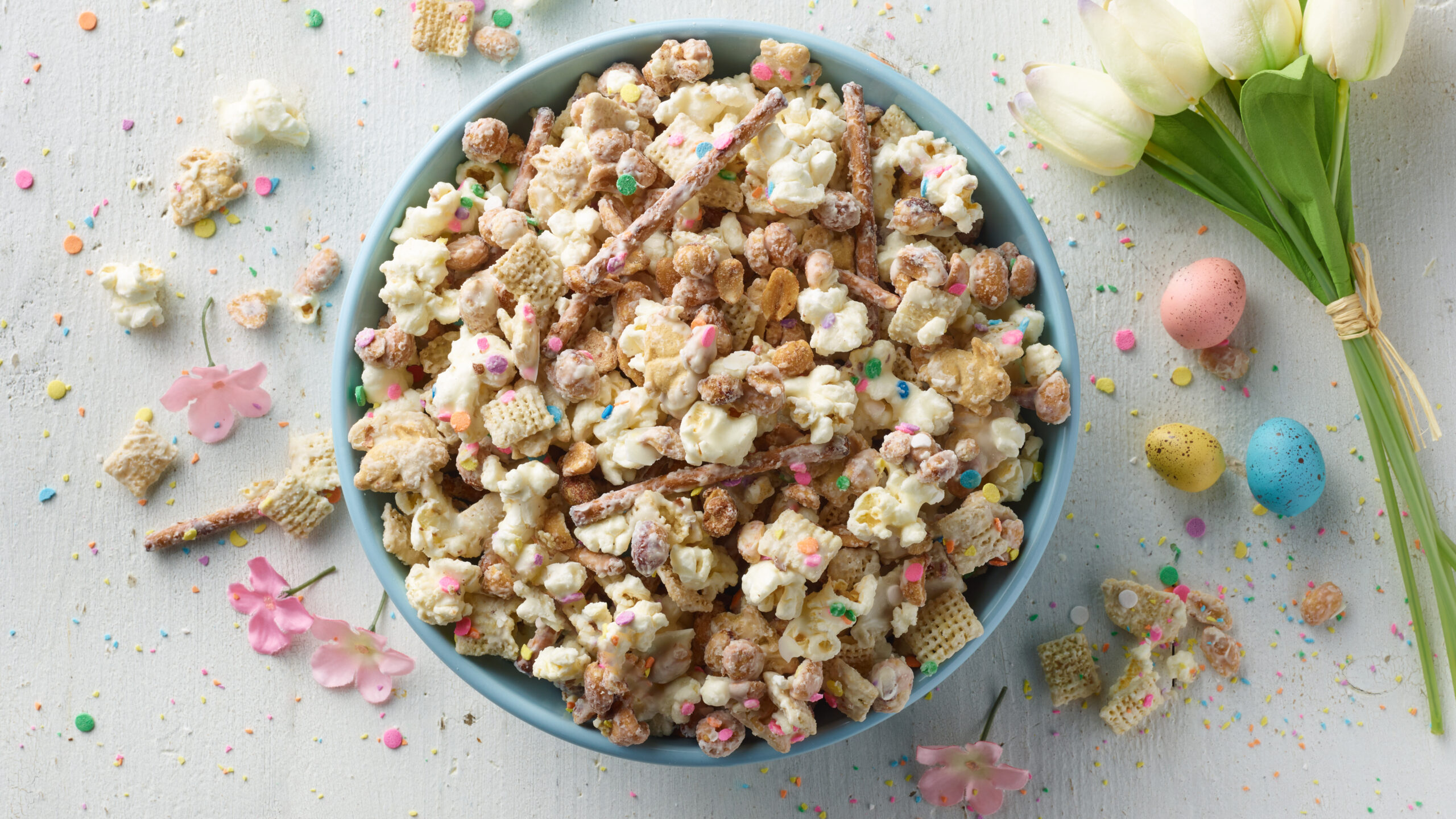 Overhead view of a spring-themed snack mix, with easter eggs, tulilps and confetti
