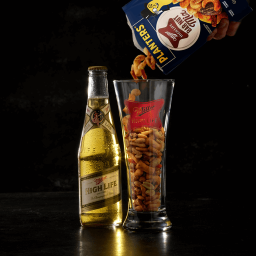 Pouring planters bar nut mix into a pint glass