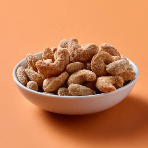A bowl of nuts over a solid orange background