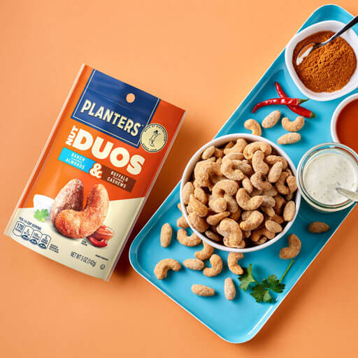 Promotional photo of planters duos ranch almonds and buffalo cashews on an orange background
