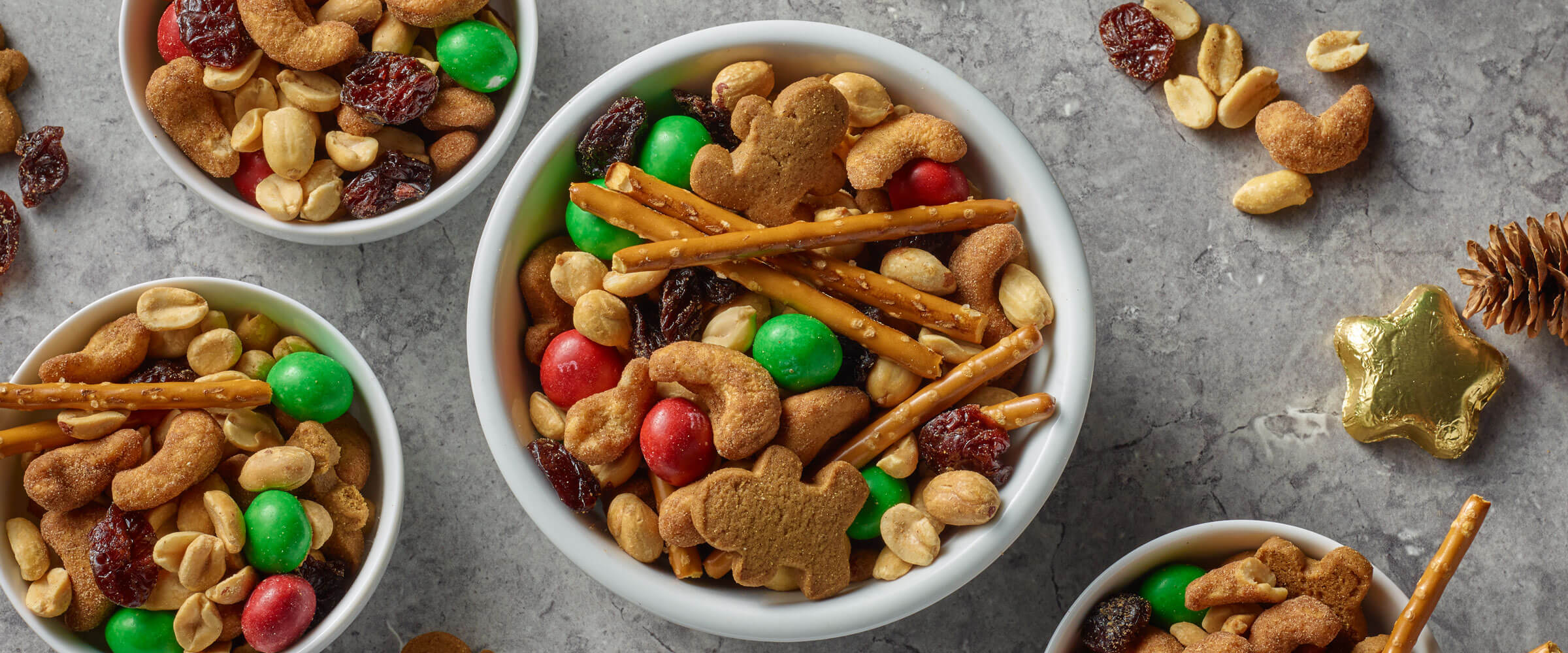 holiday snack mix recipe in a bowl with a festive spread of food on the table