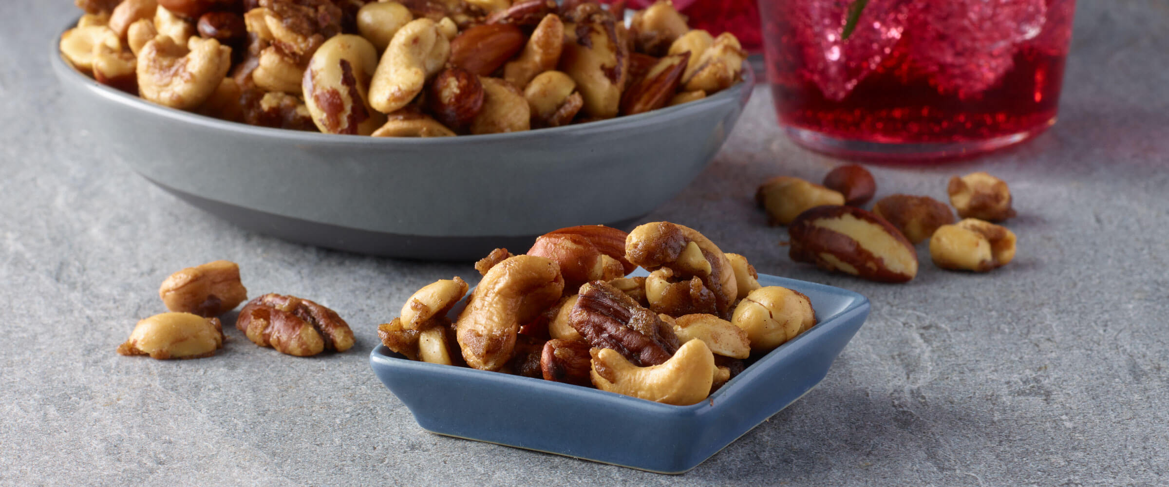 Nana’s spiced nuts recipe in a bowl on the counter with nuts spilled