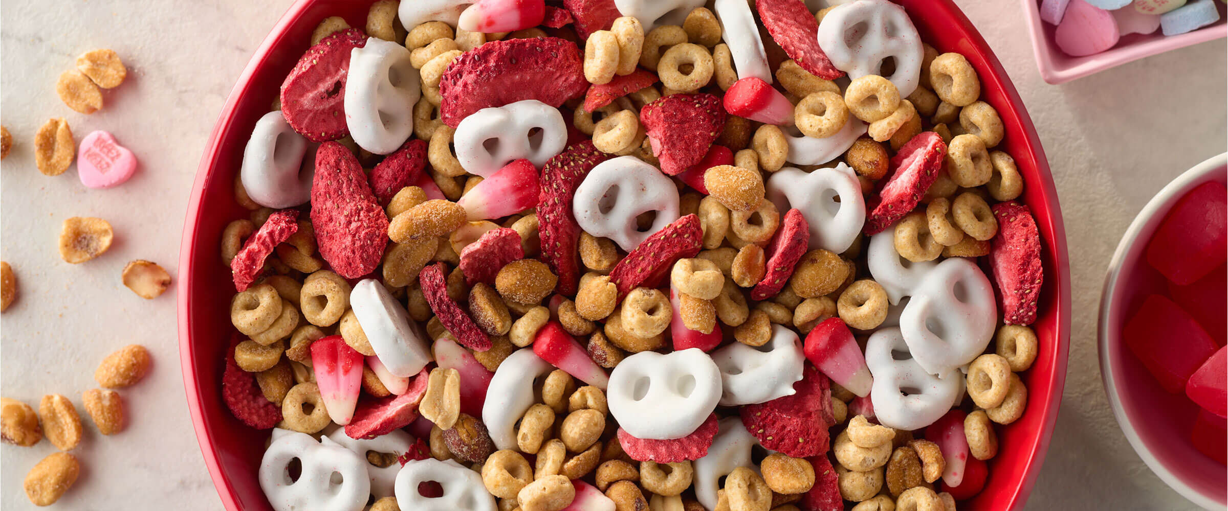 Valentines day snack mix recipe overhead view in a red bowl with nuts on the counter