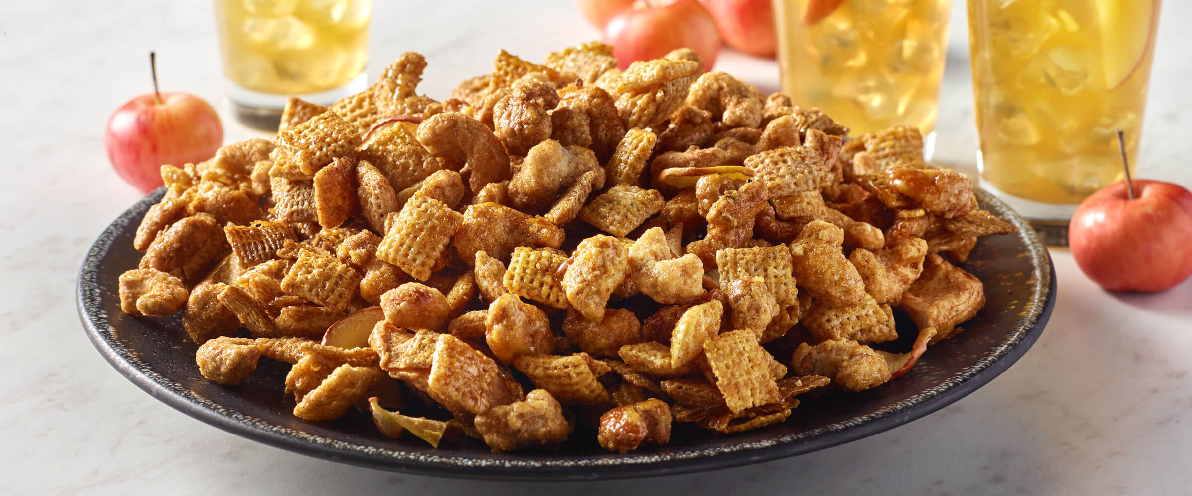 Apple cider donut cashew snack mix in a bowl with a fall setting