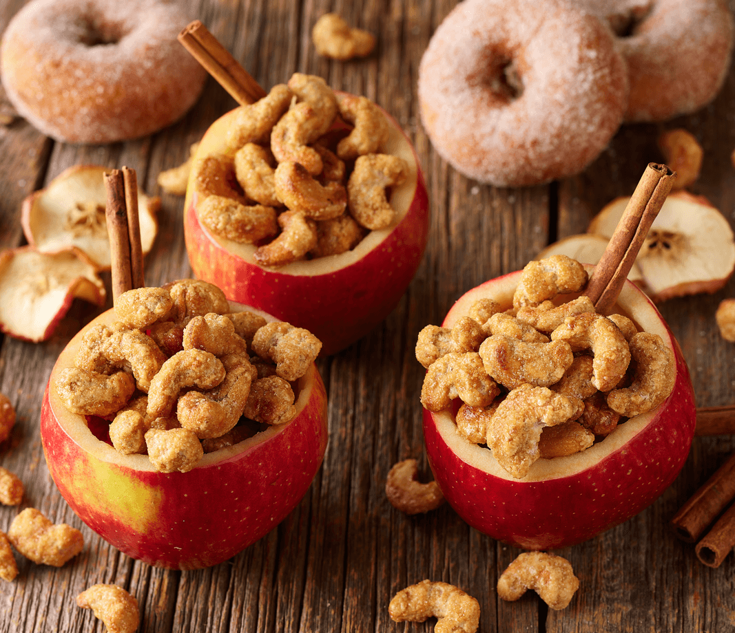 Fall promotional photo with apple cider cashews in apples with cinnamon sticks on a cutting board