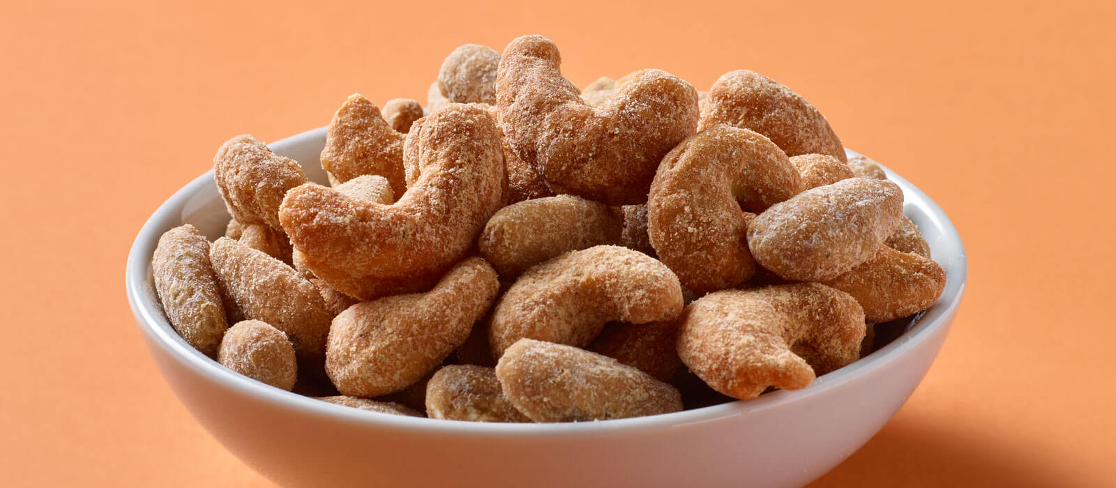 Nut Duos Buffalo Cashews and Ranch Almonds in a bowl with an orange background