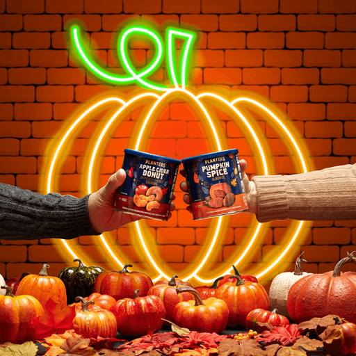 Halloween promotional photo showing fall products Two hands holding cans over an led pumpkin