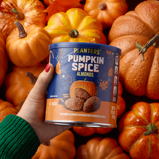 Hand holding pumpkin spice almonds over pumpkin background