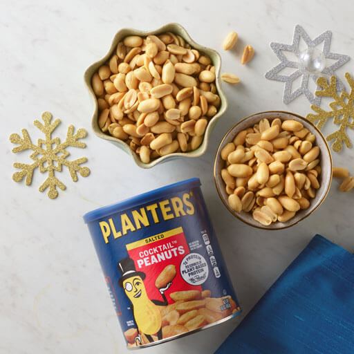 Promotional photo of Planters seasonal mixed nuts showing a can of nuts with a bowl and cut out snowflakes on the counter